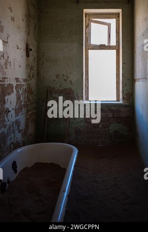 Eine antike Badewanne befindet sich im Herzen eines verlassenen Gebäudes in einer alten Wüstenstadt Stockfoto