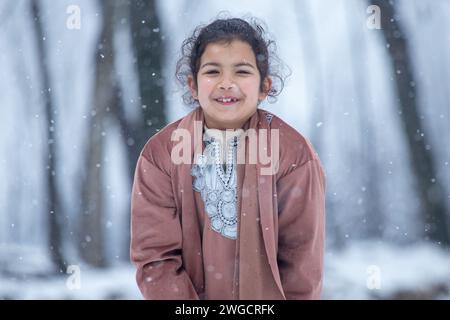 Ein Mädchen aus Kaschmir posiert für ein Foto bei frischem Schneefall in Srinagar. Mehrere Teile Kaschmirs, darunter auch die Stadt Srinagar, erhielten am Samstag Neuschnee, da die Wetterabteilung für die nächsten 48 Stunden mittelschweren bis starken Schneefall im Tal vorhersagte. Darüber hinaus haben die Behörden Lawinenwarnungen in hügeligen und bergigen Gebieten der Region ausgegeben. Stockfoto