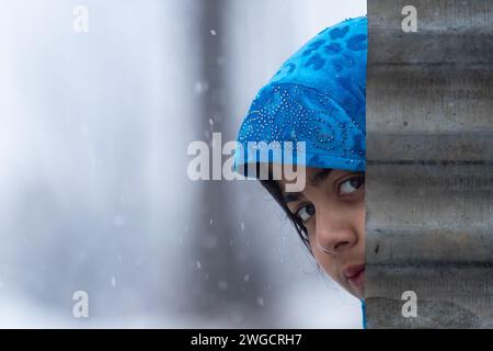 Ein Mädchen aus Kaschmir sieht bei frischem Schneefall in Srinagar zu. Mehrere Teile Kaschmirs, darunter auch die Stadt Srinagar, erhielten am Samstag Neuschnee, da die Wetterabteilung für die nächsten 48 Stunden mittelschweren bis starken Schneefall im Tal vorhersagte. Darüber hinaus haben die Behörden Lawinenwarnungen in hügeligen und bergigen Gebieten der Region ausgegeben. Stockfoto