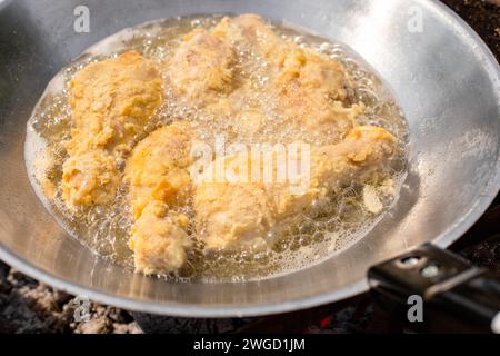 Hähnchenschenkel im Teig werden im Wok gebraten. Draußen kochen. Stockfoto