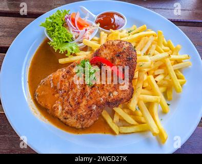 Traditionelles italienisches Kalbfleisch aus Milanese mit Zitrone und Pommes Frites in Nahaufnahme auf dem Teller Stockfoto