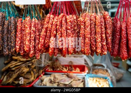 Getrocknete Wurst hängt an Fäden an einem Marktstand auf der Straße mit anderen Fleisch- und Fischprodukten Stockfoto