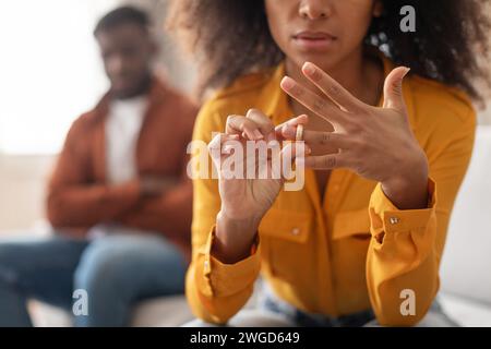 Schwarze Frau, die den Ehering abnimmt und drinnen neben dem Ehemann sitzt Stockfoto
