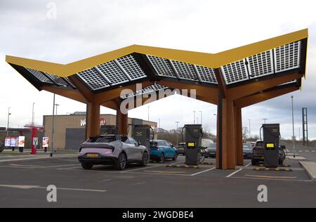 Autos mit einer Fastned Ladestation am Northern Gateway, Colchester. Fastned bietet superschnelles Laden von Elektrofahrzeugen Stockfoto