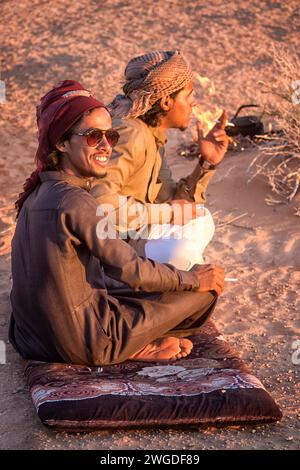 Zwei männliche beduinen sitzen und rauchen in der Wüste von Wadi Rum. Wādī Ramm (auch Wādī al-Ramm), auch bekannt als Tal des Mondes (arabisch وادي القمر Wādī al-Qamar), ist ein in Sandstein und Granitfelsen gehauenes Tal im Süden Jordaniens, nahe der Grenze zu Saudi-Arabien und etwa 60 km östlich der Stadt Aqaba. Es ist das größte Wadi in Jordanien. Stockfoto