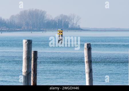 Schifffahrtsbeschreibung nach Triest oder Barbana Sanctuary. Schilder hängen in der Mitte des schiffbaren Kanals in der Lagune. Nebeliger Tag. Stockfoto