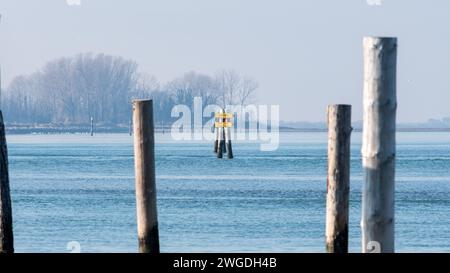 Schifffahrtsbeschreibung nach Triest oder Barbana Sanctuary. Schilder hängen in der Mitte des schiffbaren Kanals in der Lagune. Nebeliger Tag. Stockfoto