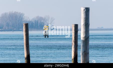 Schifffahrtsbeschreibung nach Triest oder Barbana Sanctuary. Schilder hängen in der Mitte des schiffbaren Kanals in der Lagune. Nebeliger Tag. Stockfoto