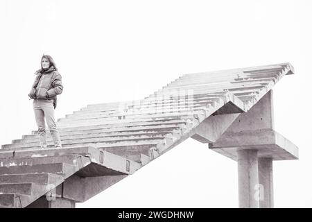 Frau, die auf der Treppe ins Nirgendwo läuft. Mädchen klettert die Treppe hoch. Person auf unvollendeter Brücke. Treppe zum Himmel. Treppen zum Erfolg. Karriereleiter. Stockfoto