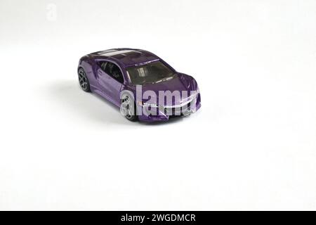 Ein Fliederauto, ein Kinderspielzeug, steht auf weißem Hintergrund. Stockfoto