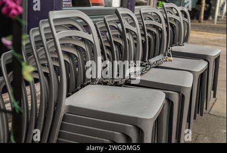 An sonnigen Tagen stehen neben der Terrasse des Cafés stapelbare silbergraue Plastikstühle. Detaillierte Darstellung von Musterstapel Kunststoffstühle, Platz für Text, Sel Stockfoto