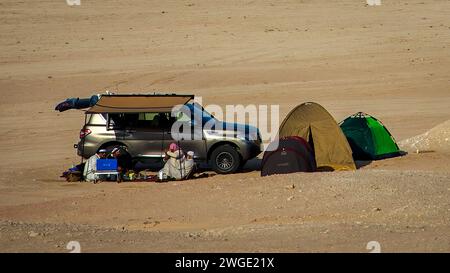 Eine kleine Gruppe von Leuten, die in der Hitze in der Wüste in der Nähe seines Autos, in einem Zelt in der Nähe von Dhahran, Saudi-Arabien, liegen. Stockfoto