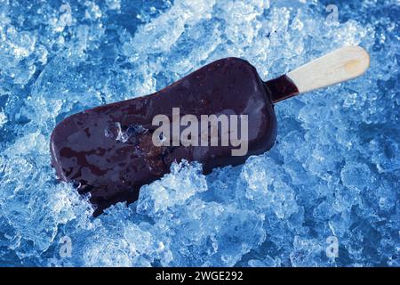 Eine Eiscreme Auf Holzstab, Beschichtet Mit Schokoladenglasur. Kaltes Dessert Auf Natürlichen Eiskristallen. Stockfoto