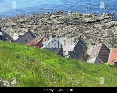 Malerisches und abgelegenes NE Schottland: Die ehemaligen Fischerhütten Klammern sich am Fuß der Klippen vor der felsigen Nordseeküste bei Crovie. Stockfoto