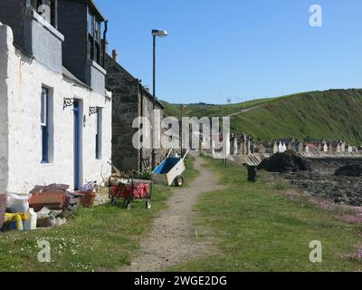 Schubkarren und Karren sind das einzige Mittel, um Waren den steilen Hügel hinunter zu den Hütten zu transportieren, die das kleine Fischerdorf Crovie ausmachen. Stockfoto