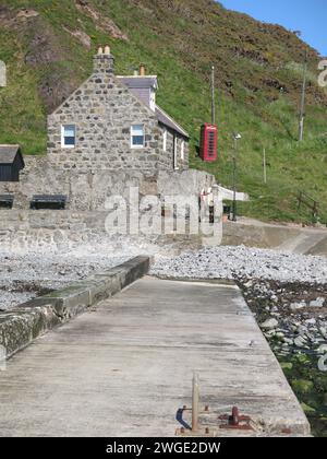 Schottische Landschaften: Ein malerischer Blick auf das kleine ehemalige Fischerdorf Crovie mit seinen aus Stein gebauten Cottages und einer einzigen roten Telefonzelle. Stockfoto