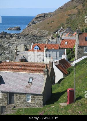 Schottische Landschaften: Ein malerischer Blick auf das kleine ehemalige Fischerdorf Crovie mit seinen aus Stein gebauten Cottages und einer einzigen roten Telefonzelle. Stockfoto