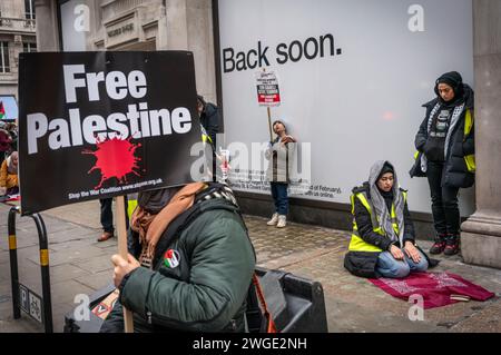 London, Großbritannien. Februar 2024. Das Banner des freien Palästina wurde von einer Friedensaktivistin/Demonstrantin und einer muslimischen Frau gehalten, die während des Pro - Palästina-marsches in der Nähe der Oxford Street in Soho, Freie Palästina-Bewegung, London, Großbritannien, betete Stockfoto