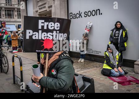 London, Großbritannien. Februar 2024. Das Banner des freien Palästina wurde von einer Friedensaktivistin/Demonstrantin und einer muslimischen Frau gehalten, die während des Pro - Palästina-marsches in der Nähe der Oxford Street in Soho, Freie Palästina-Bewegung, London, Großbritannien, betete Stockfoto