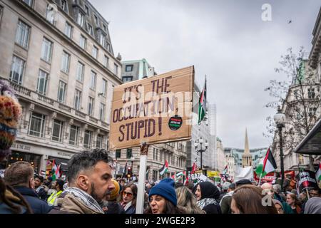 London, Großbritannien. Februar 2024. Anti-Okkupation-Banner eines männlichen Friedensaktivisten/Demonstranten während des Pro - Palestine marsches in der Nähe der Oxford Street in Soho, Freie Palästina-Bewegung, London, Großbritannien Stockfoto