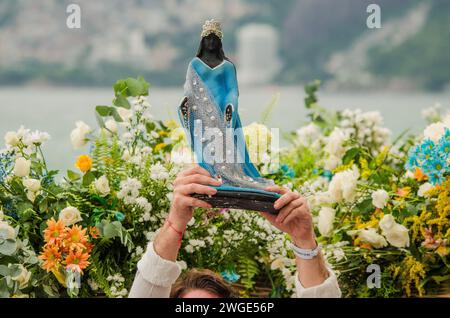 Ein Gläubiger hält die Statue von Iemanjá mit Blumen hinter dem Tag von Iemanjá. Jedes Jahr versammeln sich Brasilianer aller Glaubensrichtungen, um die Candomblé-Göttin Iemanjá zu feiern. Am 2. Februar versammelten sie sich, um den Iemanjá-Tag in allen Teilen Brasiliens zu feiern. In Rio de Janeiro ist eine der wichtigsten Feierlichkeiten für orixá Iemanjá und fand am Strand von Arpoador statt. Der Tag von Iemanjá ist eine Feier über die Kultur und Ahnengeschichte der Schwarzen und die Geschichte der Diaspora und feiert die Musik, Kunst und Sprache. Stockfoto