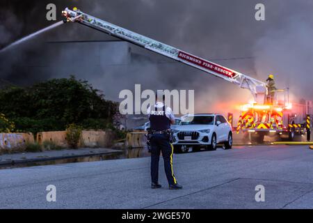 RICHMOND, BC, KANADA - 27. JULI 2023: Richmond Feuerwehrleute und Löschfahrzeuge bekämpfen ein tosendes Feuer, Rettungsdienste, Ersthelfer, Rauch, Wasser Stockfoto