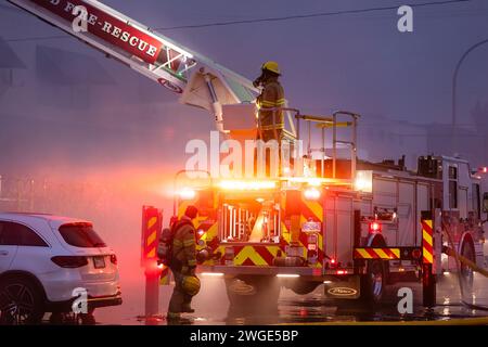 RICHMOND, BC, KANADA - 27. JULI 2023: Richmond Feuerwehrleute und Löschfahrzeuge bekämpfen ein tosendes Feuer, Rettungsdienste, Ersthelfer, Rauch, Wasser Stockfoto