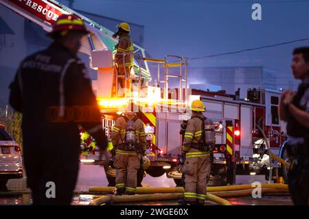 RICHMOND, BC, KANADA - 27. JULI 2023: Richmond Feuerwehrleute und Löschfahrzeuge bekämpfen ein tosendes Feuer, Rettungsdienste, Ersthelfer, Rauch, Wasser Stockfoto