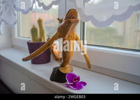 Ein Baumzweig, der aussieht wie ein Drache an einem Fenster mit einer Blume Stockfoto
