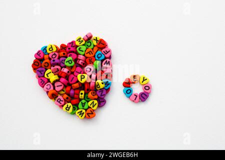 Phrase Love You neben einem Herz, das mit bunten Perlen geformt ist, um Halsketten und Armbänder zu machen Stockfoto