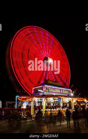 Niederländisches Rad. Riesenrad. Karnevalsfahrt mit Bewegungsunschärfe bei langer Belichtung. Ballon-A-Rama-Karnevalszelt im Vordergrund. Canfield Fair, Mahoning Coun Stockfoto