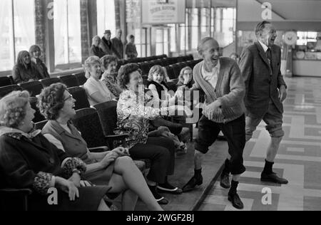 1970er Jahre Butlins Ferienlager Großbritannien. Zwei Urlauber mit hochgerollten Hosenbeinen nehmen an dem besten und feststen Wettkampf der Wadenmuskulatur Teil, was bei ihren beobachtenden Frauen viel Spaß macht. Bognor Regis, West Sussex, England 1972. HOMER SYKES Stockfoto