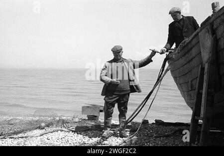 Küstenfischerei 1960er Jahre Großbritannien. Fisherman Charlie Tart arbeitet an ein paar leichten Reparaturen an diesem Boot. Die Tart-Familie und die Olier’s sind die beiden bekanntesten Fischerfamilien in Dungeness, sie leben und fischen seit dem frühen 20. Jahrhundert am Kieselstrand. Dungeness, Kent England 1969 HOMER SYKES. Stockfoto