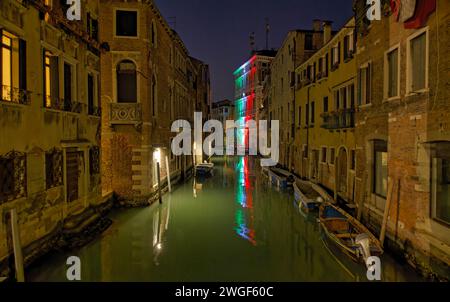 Dämmerungsserenade in Venedigs mystischem Kanal und Gebäude mit italienischer Flagge Stockfoto