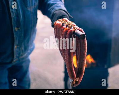 Geräucherte Fleischwürste, die gerade von einem kleinen Hausraucher genommen wurden. Hausgemachte Würstchen Stockfoto