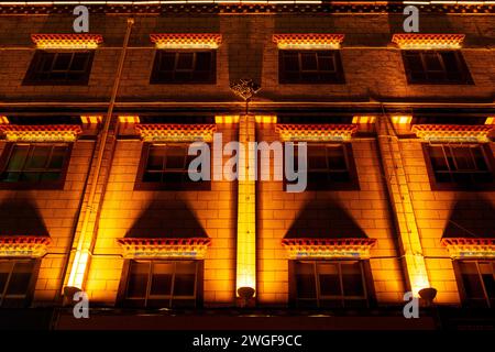 Ein goldener Lichtguss ziert ein Ziegelgebäude in Lhasa City bei Nacht. Stockfoto