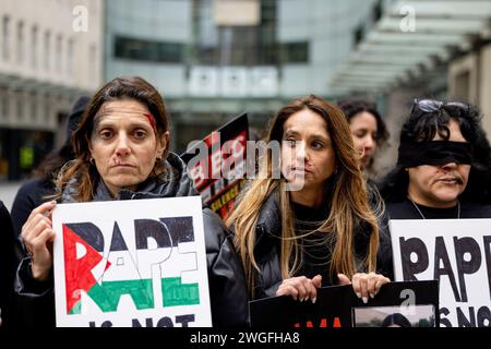 Demonstrantinnen bedecken ihre Augen und tragen künstliche Wunden Make-up, während sie Plakate halten, um gegen die Behandlung weiblicher Geiseln zu demonstrieren, die sich noch in Gefangenschaft der Hamas befinden, während einer Kundgebung vor dem BBC-Hauptquartier in London. Israelische Unterstützer versammeln sich im Hauptquartier der BBC zu einer Kundgebung, um einen fairen Bericht über den Israel-Hamas-Krieg zu fordern und die Hamas-Streitkräfte zur Freilassung der restlichen Geiseln im Gaza-Streifen zu drängen. Der Konflikt brach im Nahen Osten aus, nachdem Hamas-Truppen am 7. Oktober 2023 eine örtliche Gemeinde in Südisrael überfallen und mehr als 200 Geiseln gefangen genommen und Hunderte weitere getötet hatten. Stockfoto