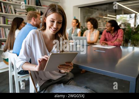 Lächelnd treffen sich verschiedene Kollegen in einem Brainstorming in der Vorstandsetage, um gemeinsam Finanzstatistiken zu diskutieren Stockfoto