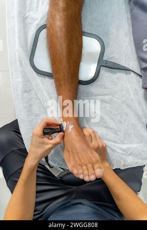 Die obere Nahaufnahme einer Hand, die Ultraschall am Knöchel aufsetzt Stockfoto