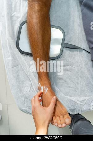 Nahaufnahme einer Hand, die Creme auf den Knöchel legt Stockfoto