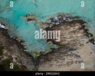 Blick aus der Vogelperspektive auf die felsige Küste von La Pelosa Beach in Sassari, Sardinien. Sandstrand, türkisfarbenes Wasser und Küstengrün. Stockfoto