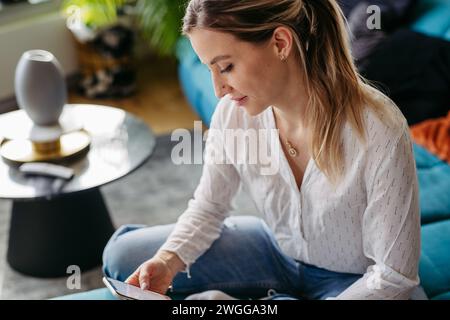 Krankenschwester oder Ärztin, die nach der Arbeit Freizeit zu Hause genießt. Porträt einer schönen Frau mit Smartphone in der Hand. Stockfoto