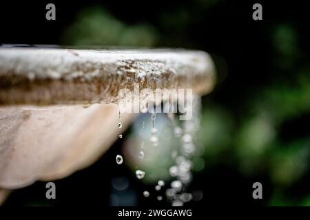BRUNNEN und WASSERFLUSS in natürlichem, wunderschönem Licht. Nahaufnahme von Tropfen und Wasserelement als beruhigende Energie. Stockfoto
