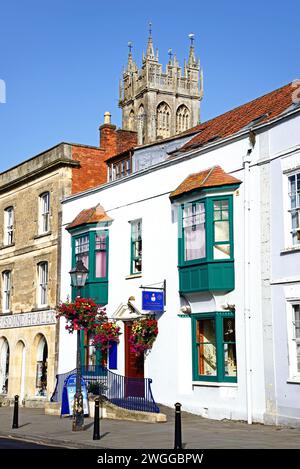 Spirituelles Zentrum entlang der High Street im Stadtzentrum mit dem Kirchturm St. John the Baptist auf der Rückseite, Glastonbury, Großbritannien. Stockfoto