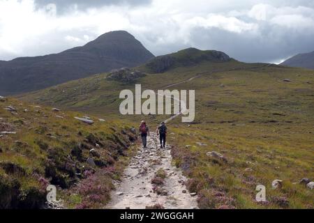 Two Men (Wanderer) Walking on Track zum Scottish Mountain Corbett 'Beinn an Eoin' Flowerdale Forest, Wester Ross, North West Highlands, Schottland, Großbritannien. Stockfoto