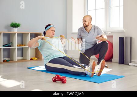 Übergewichtige Frau, die mit ihrem Trainer im Fitnessclub Fitness-Training macht Stockfoto