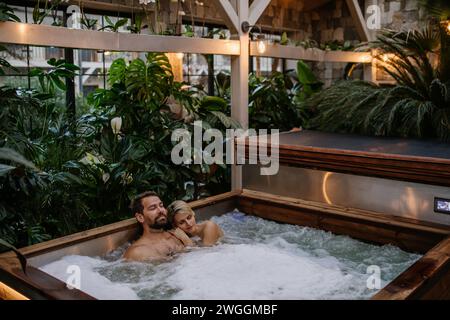 Wunderschönes, reifes Paar, das sich im Whirlpool entspannt und ein romantisches Wellnesswochenende im Spa genießt. Valentinstag-Konzept. Stockfoto