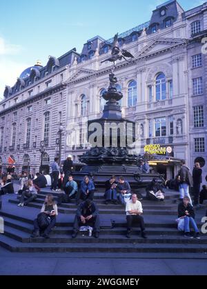 Großbritannien, London, Piccadilly Circus in der Abenddämmerung machen müde Einkäufer eine Pause an der Statue (Shaftesbury Memorial Fountain). Stockfoto