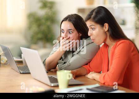 Schockierte Tele-Mitarbeiter, die zu Hause einen Laptop überprüfen Stockfoto