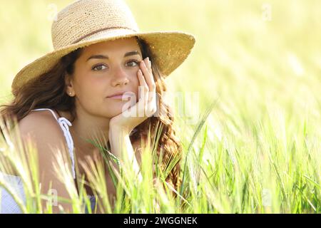 Porträt einer ernsten Frau mit pamela-Hut, die dich auf einem Feld ansieht Stockfoto